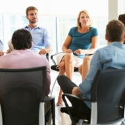 Business meeting with people sat on chairs in a circle.